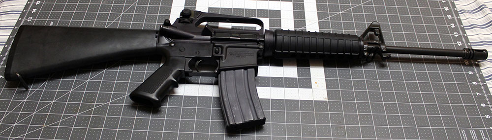 right side view of a Colt AR-15 Lightweight rifle, lying on a crafting mat for scale
